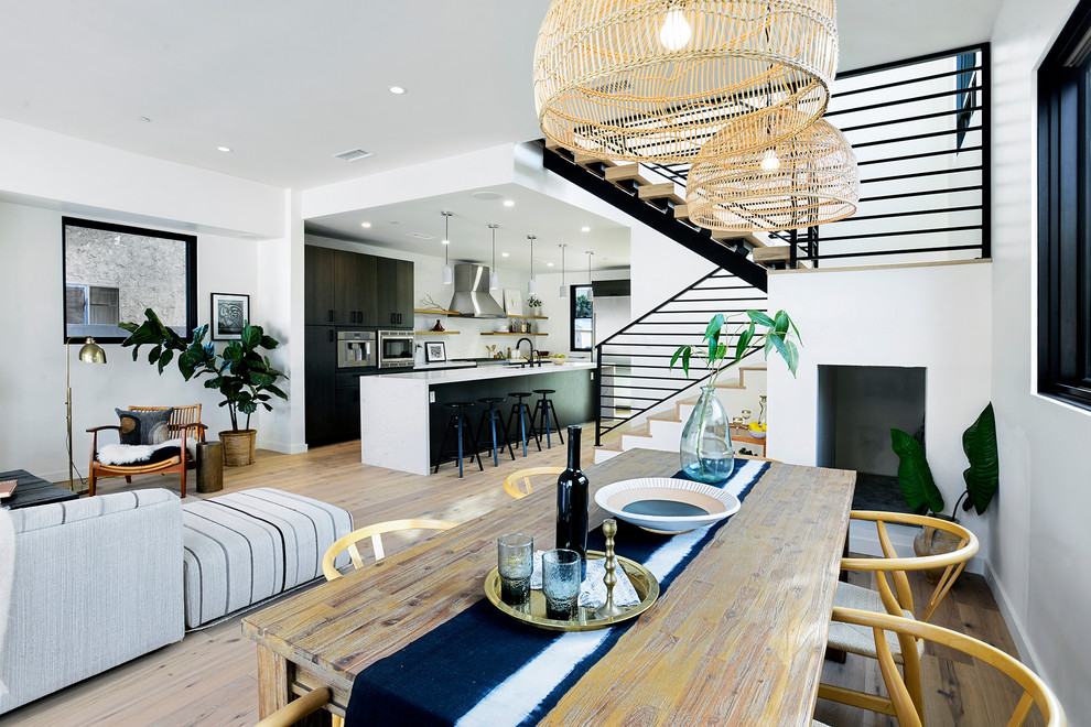 This is an example of a mid-sized modern open plan dining in Los Angeles with white walls and light hardwood floors.