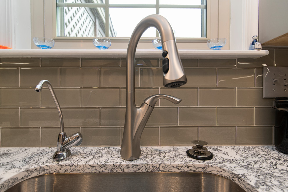 Example of a mid-sized transitional l-shaped brown floor eat-in kitchen design in Baltimore with a single-bowl sink, shaker cabinets, gray cabinets, quartz countertops, gray backsplash, subway tile backsplash, stainless steel appliances, an island and white countertops