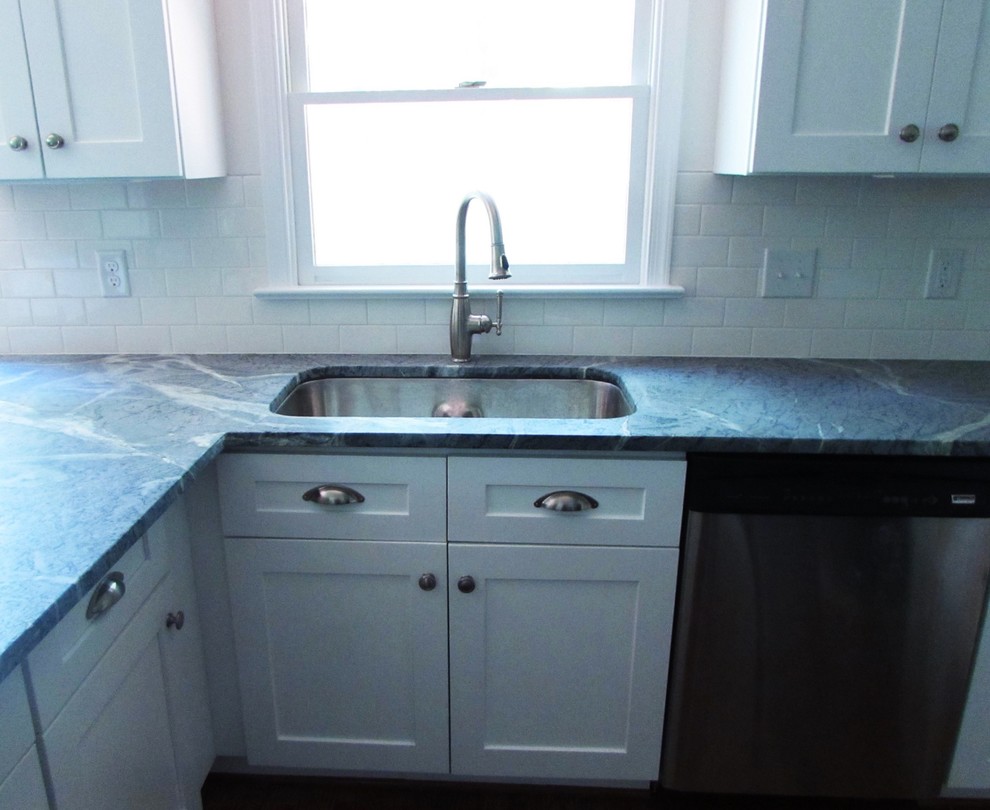 Example of a mid-sized transitional l-shaped medium tone wood floor enclosed kitchen design with an undermount sink, shaker cabinets, white cabinets, soapstone countertops, white backsplash, subway tile backsplash, stainless steel appliances and a peninsula