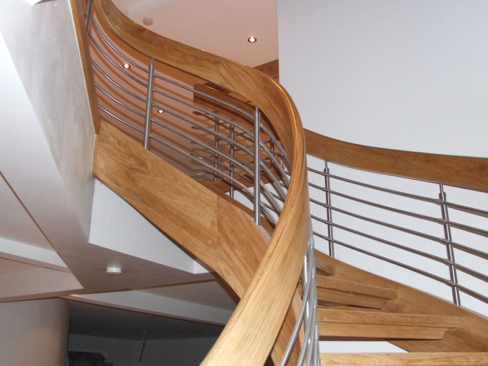 Medium sized modern wood curved mixed railing staircase in London with wood risers.