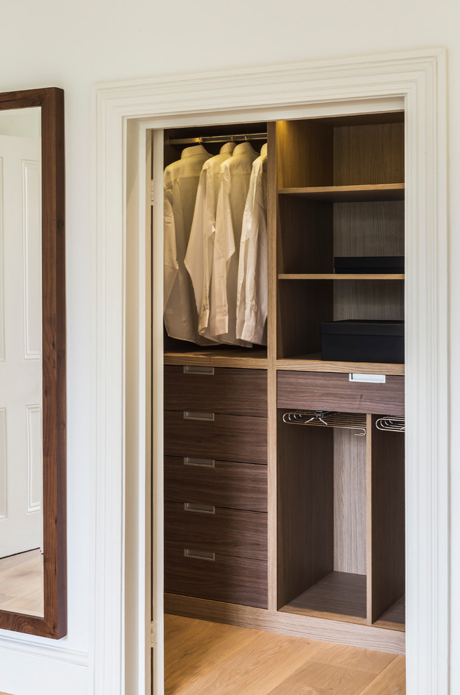 Design ideas for a mid-sized contemporary gender-neutral walk-in wardrobe in London with flat-panel cabinets, medium wood cabinets, medium hardwood floors and beige floor.