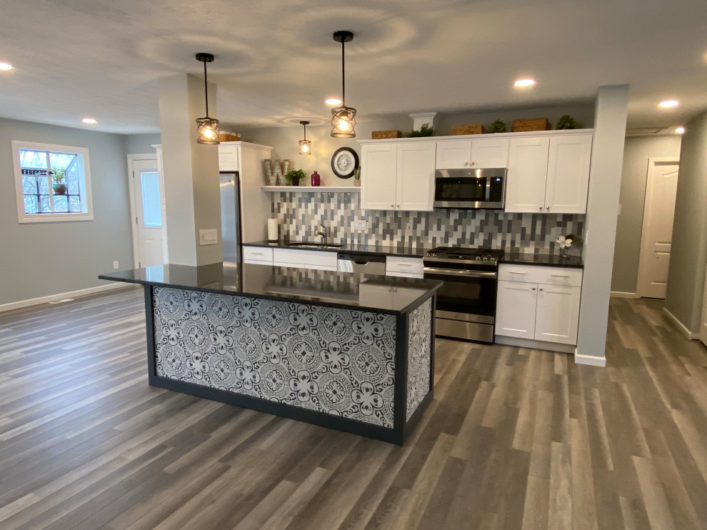 Example of a large transitional l-shaped vinyl floor and gray floor open concept kitchen design in Cincinnati with an undermount sink, raised-panel cabinets, white cabinets, granite countertops, multicolored backsplash, ceramic backsplash, stainless steel appliances, an island and black countertops