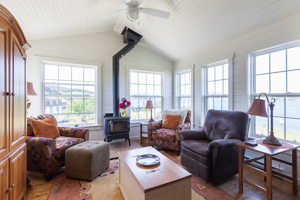 Photo of a beach style sunroom in Other with medium hardwood floors, a wood stove, a standard ceiling and brown floor.