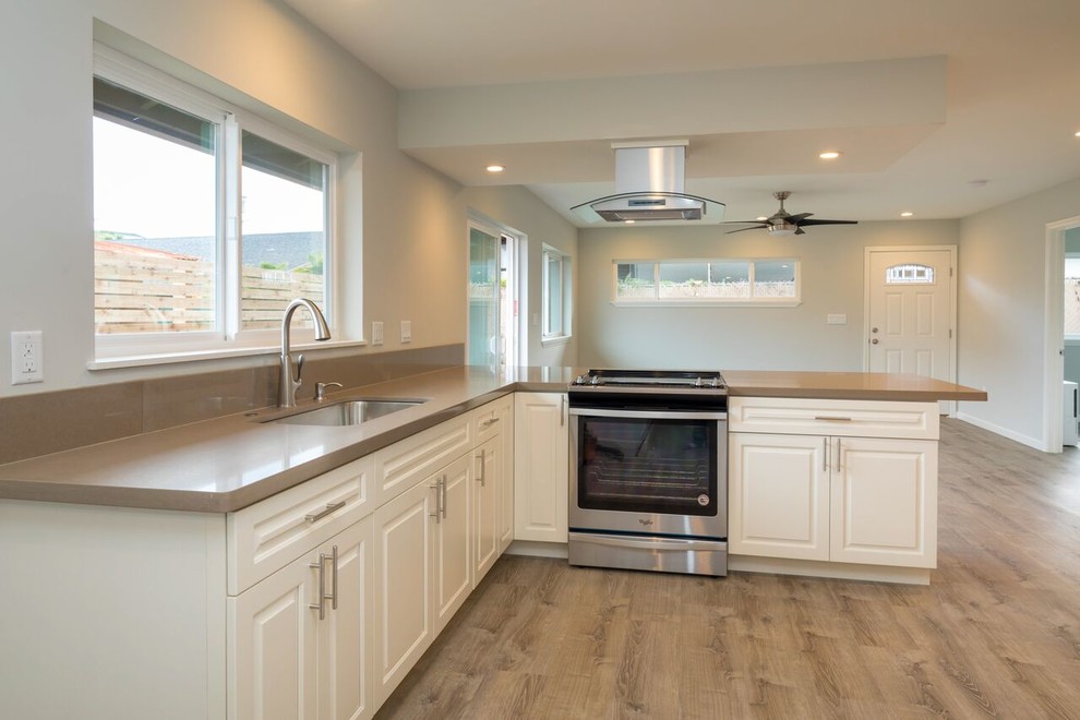 Mid-sized beach style u-shaped open plan kitchen in Hawaii with an undermount sink, shaker cabinets, white cabinets, granite benchtops, stainless steel appliances, ceramic floors, a peninsula and beige floor.