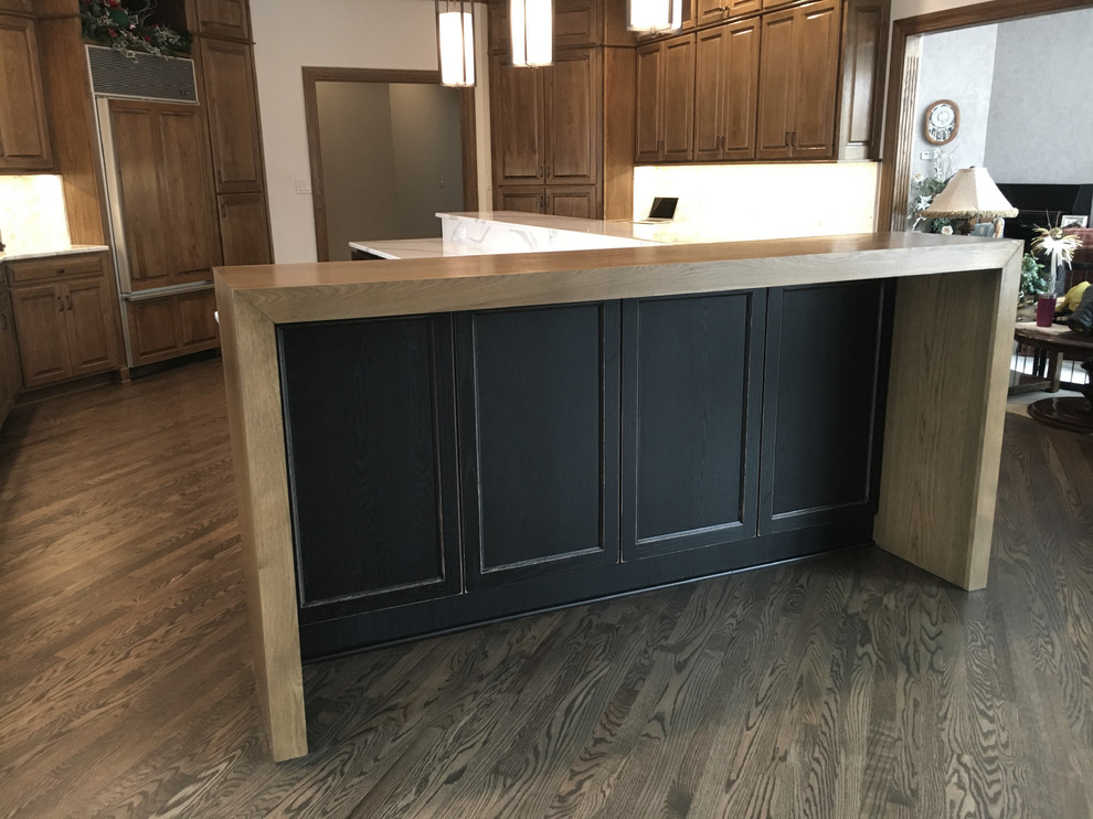 Example of a large transitional u-shaped medium tone wood floor home design design with an undermount sink, recessed-panel cabinets, distressed cabinets, quartz countertops, multicolored backsplash, mosaic tile backsplash, stainless steel appliances and an island