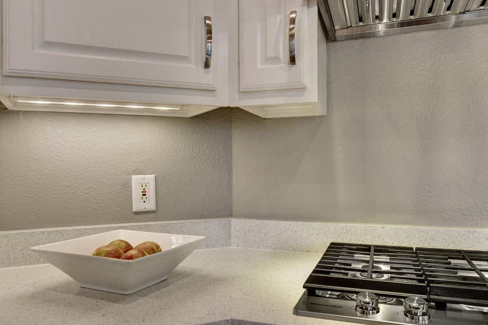 Mid-sized transitional u-shaped light wood floor eat-in kitchen photo in Austin with an undermount sink, white cabinets, quartz countertops, white backsplash, stone slab backsplash, stainless steel appliances, a peninsula and raised-panel cabinets