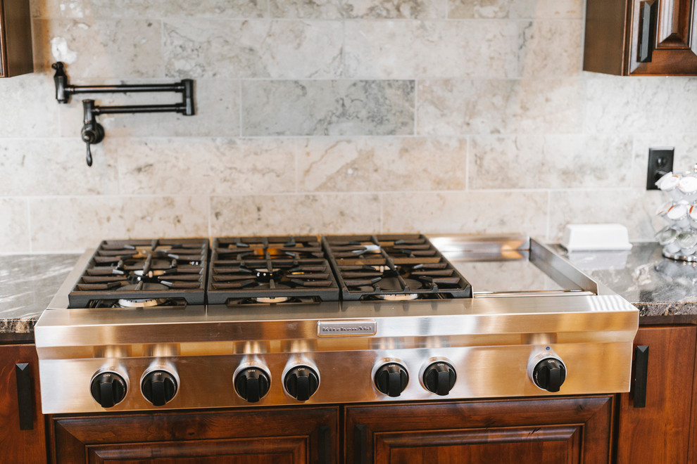 Transitional kitchen photo with dark wood cabinets, quartz countertops, beige backsplash, custom tile backsplash and stainless steel appliances