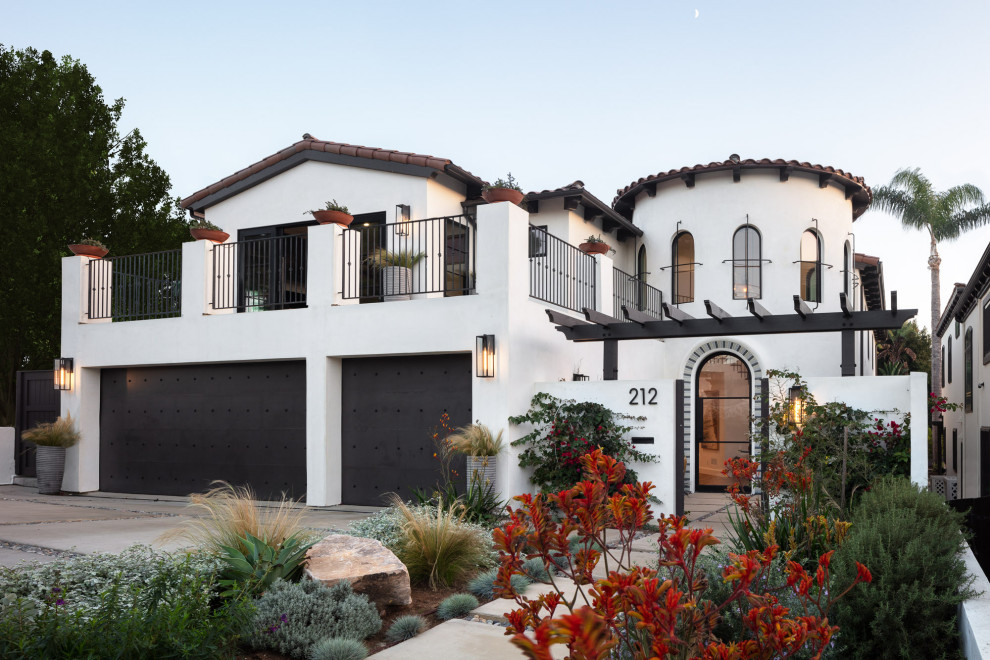 Photo of a large mediterranean two-storey stucco white house exterior in Los Angeles with a tile roof and a brown roof.