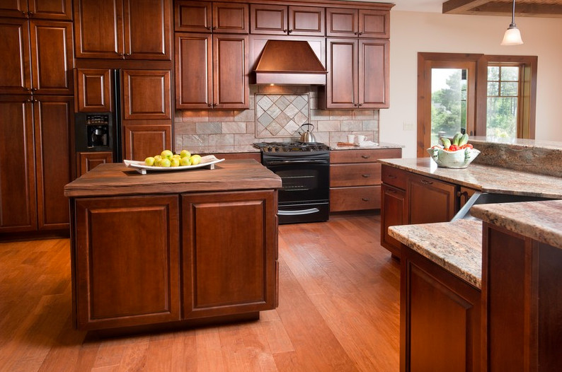 Open concept kitchen - large craftsman u-shaped medium tone wood floor and brown floor open concept kitchen idea with a farmhouse sink, shaker cabinets, medium tone wood cabinets, granite countertops, multicolored backsplash, slate backsplash, stainless steel appliances and an island