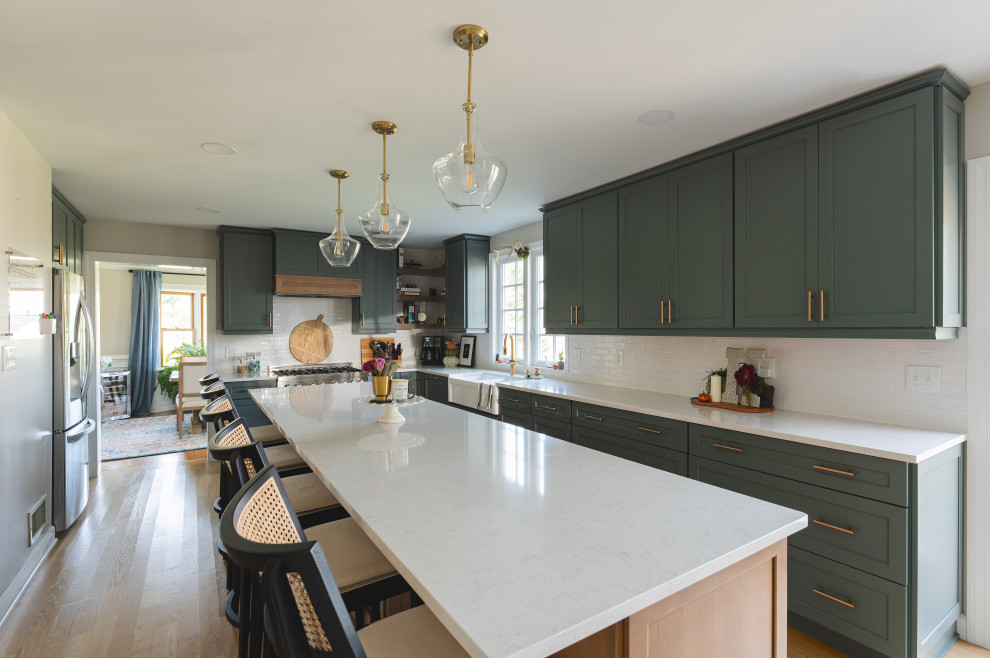 Inspiration for a large contemporary u-shaped kitchen/diner in Other with a belfast sink, shaker cabinets, green cabinets, engineered stone countertops, white splashback, metro tiled splashback, stainless steel appliances, light hardwood flooring, an island, orange floors and white worktops.
