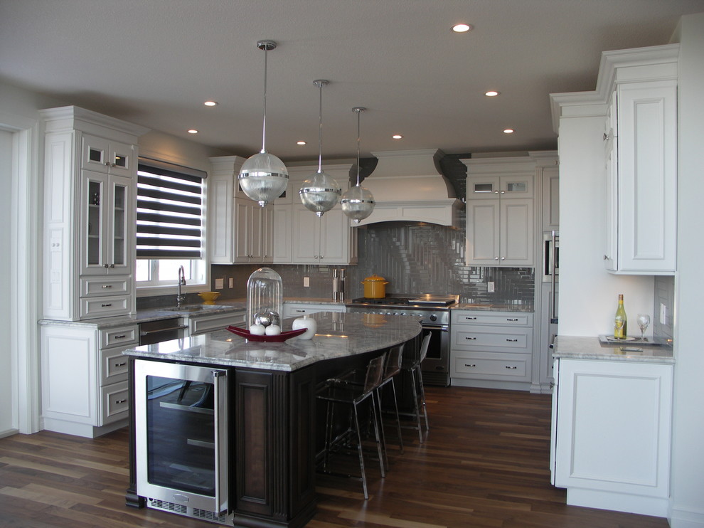 Photo of a large transitional u-shaped open plan kitchen in Edmonton with an undermount sink, recessed-panel cabinets, white cabinets, granite benchtops, grey splashback, glass tile splashback, stainless steel appliances, medium hardwood floors, with island and brown floor.