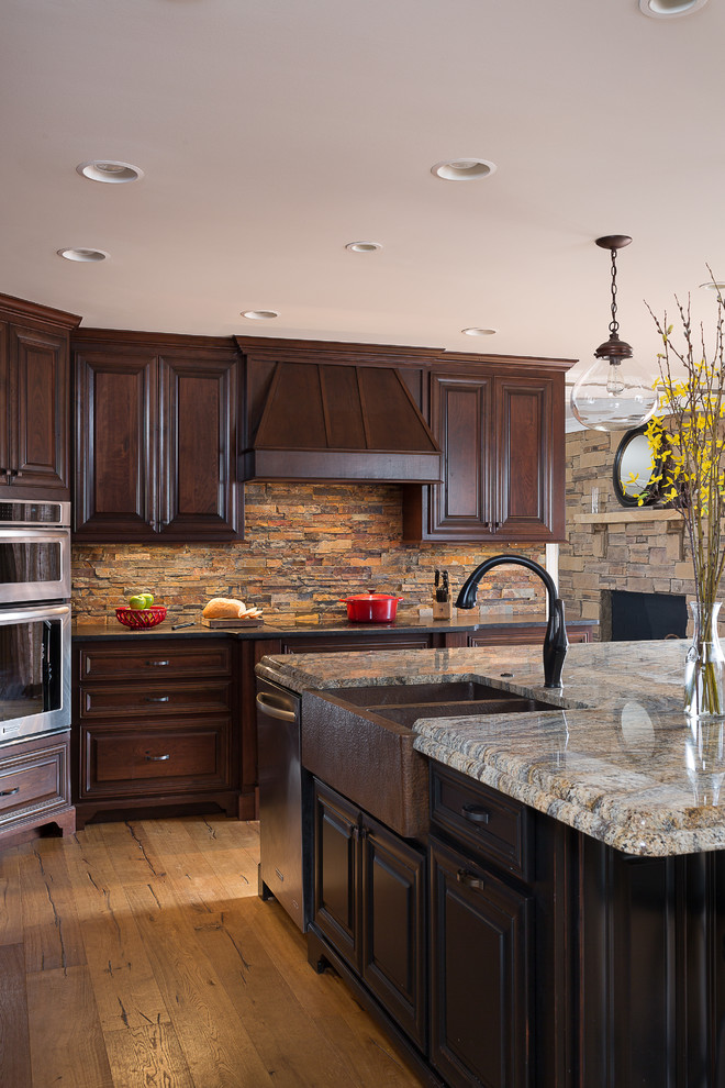 Large country u-shaped eat-in kitchen in Atlanta with a farmhouse sink, raised-panel cabinets, dark wood cabinets, granite benchtops, multi-coloured splashback, stone tile splashback, stainless steel appliances, porcelain floors and with island.