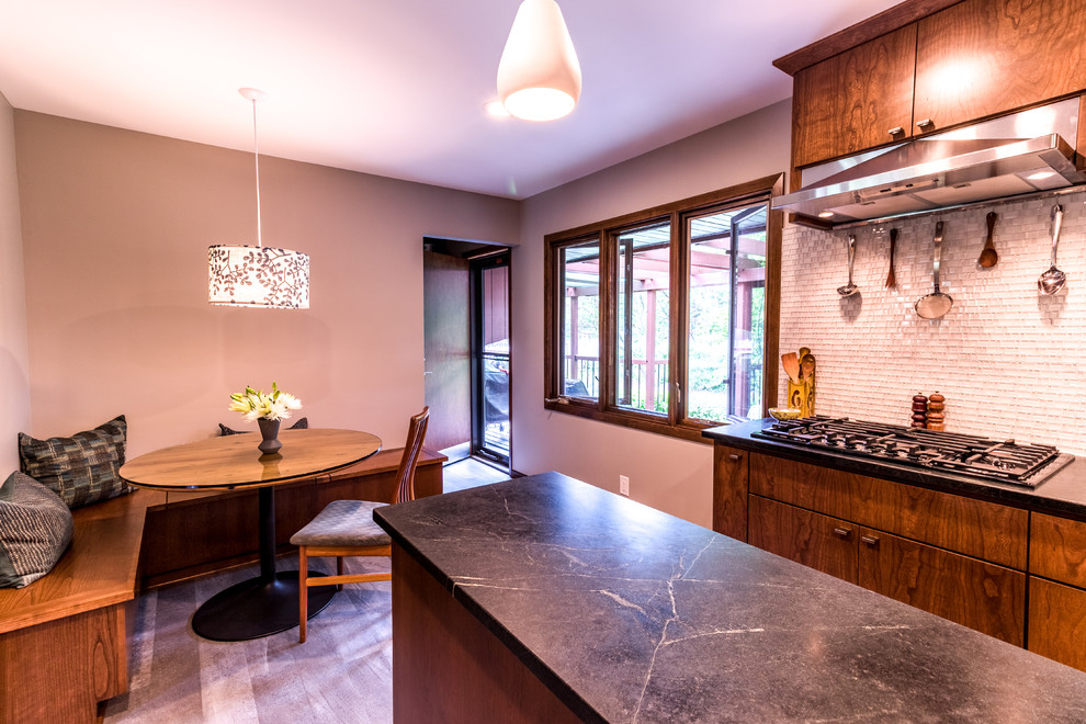 Photo of a midcentury galley eat-in kitchen with an undermount sink, flat-panel cabinets, medium wood cabinets, soapstone benchtops, white splashback, mosaic tile splashback, stainless steel appliances, vinyl floors and grey floor.