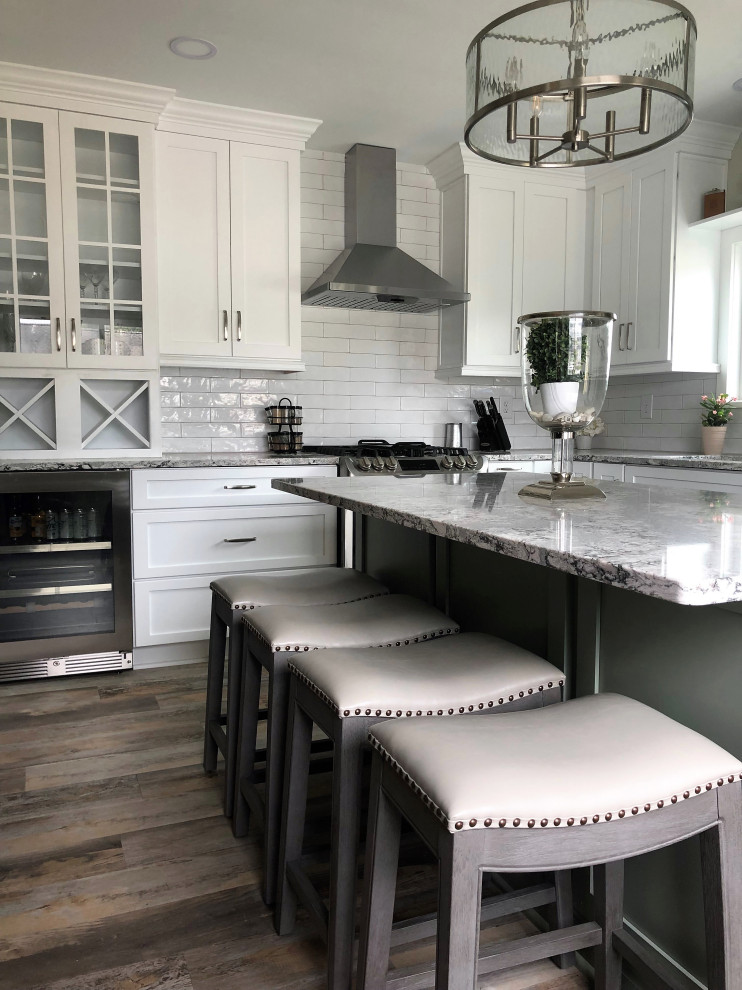 Example of a mid-sized transitional l-shaped vinyl floor and multicolored floor eat-in kitchen design with an undermount sink, flat-panel cabinets, green cabinets, quartz countertops, white backsplash, ceramic backsplash, stainless steel appliances, an island and gray countertops