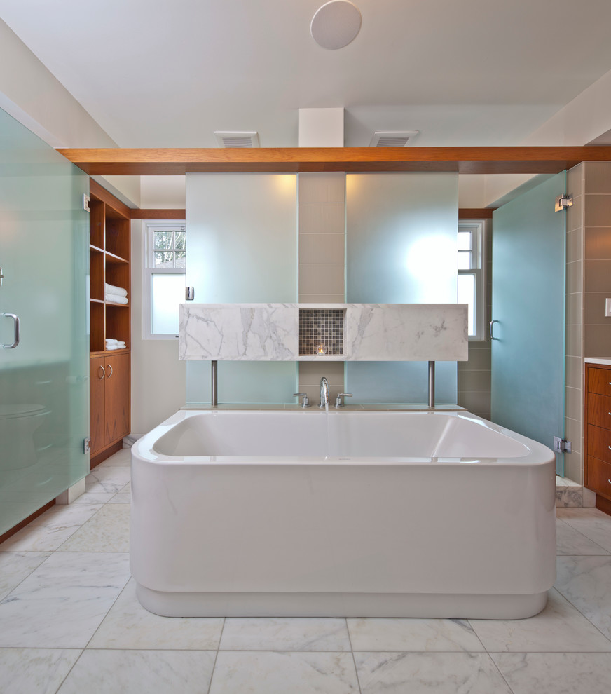 This is an example of a contemporary master bathroom in Seattle with medium wood cabinets, a freestanding tub, an alcove shower, marble floors and a hinged shower door.