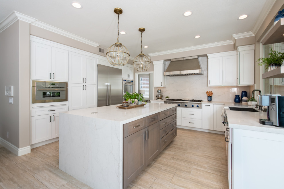 Eat-in kitchen - mid-sized transitional u-shaped brown floor eat-in kitchen idea in Orange County with a farmhouse sink, recessed-panel cabinets, white cabinets, quartz countertops, white backsplash, quartz backsplash, stainless steel appliances, an island and white countertops