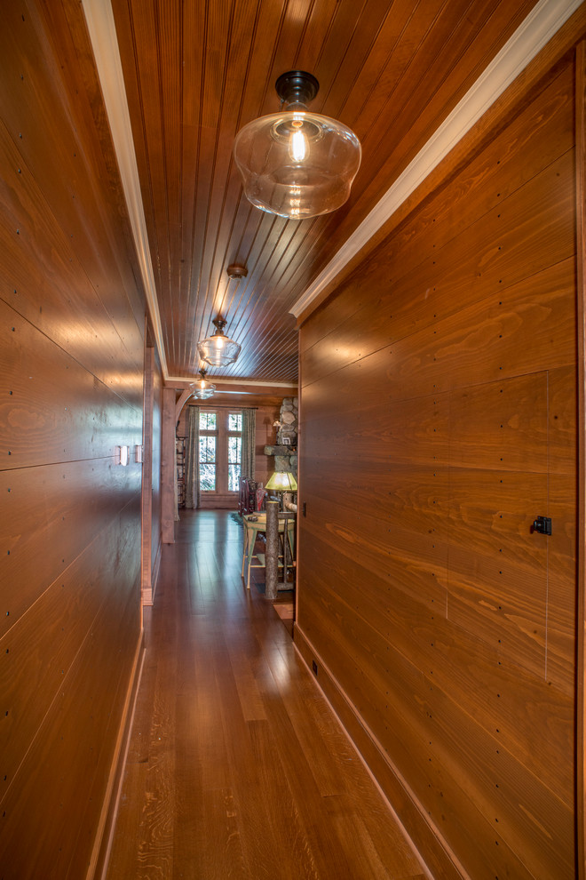 Mid-sized country hallway in New York with brown walls, dark hardwood floors and brown floor.