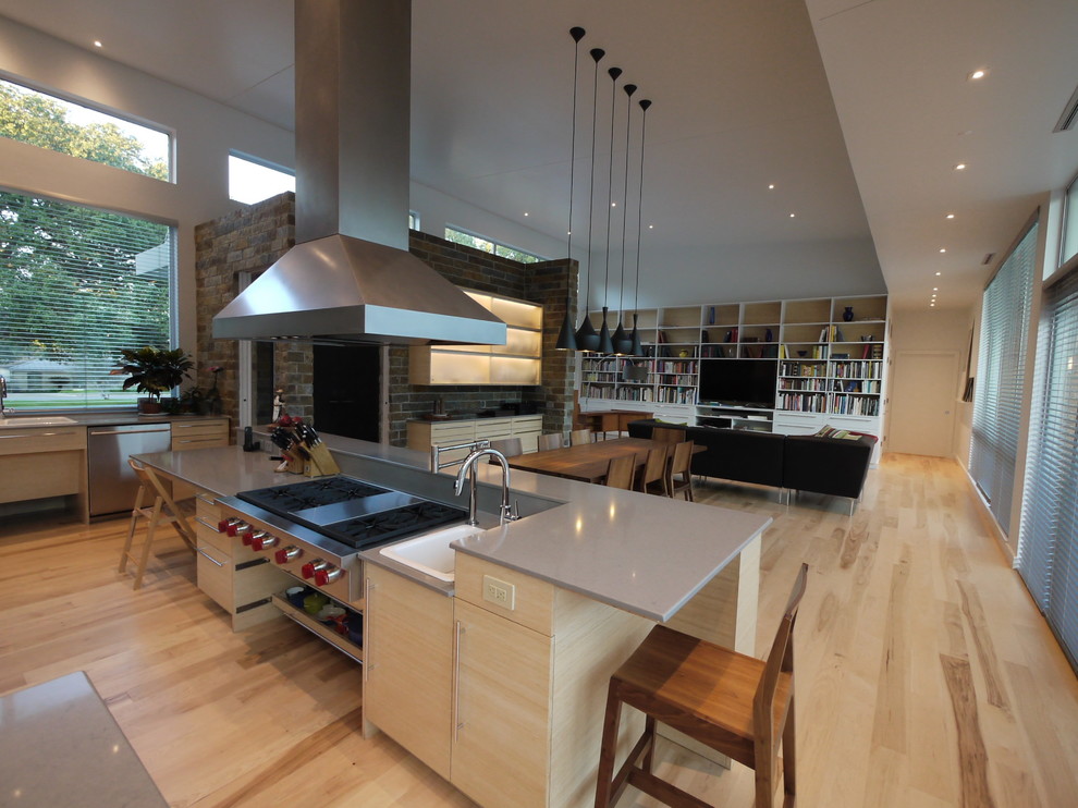 This is an example of a large modern u-shaped eat-in kitchen in Houston with flat-panel cabinets, quartz benchtops, grey splashback, stainless steel appliances, medium hardwood floors, multiple islands and grey benchtop.