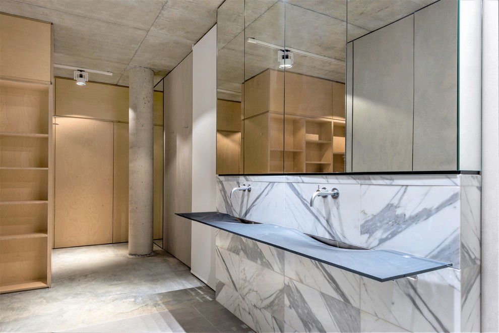 Design ideas for an industrial master bathroom in Perth with glass-front cabinets, multi-coloured tile, concrete floors, an integrated sink, glass benchtops and grey floor.