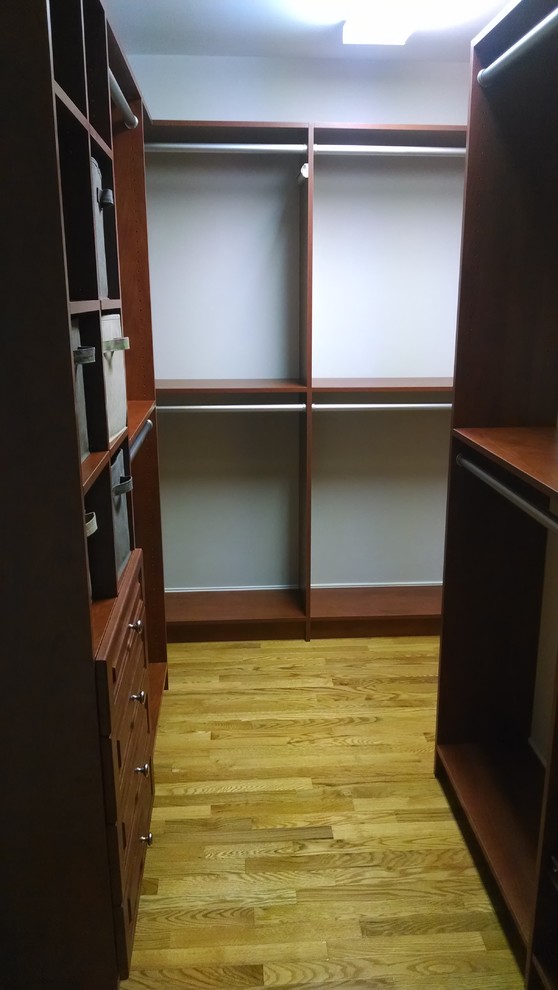 Photo of a mid-sized walk-in wardrobe in Other with medium wood cabinets.