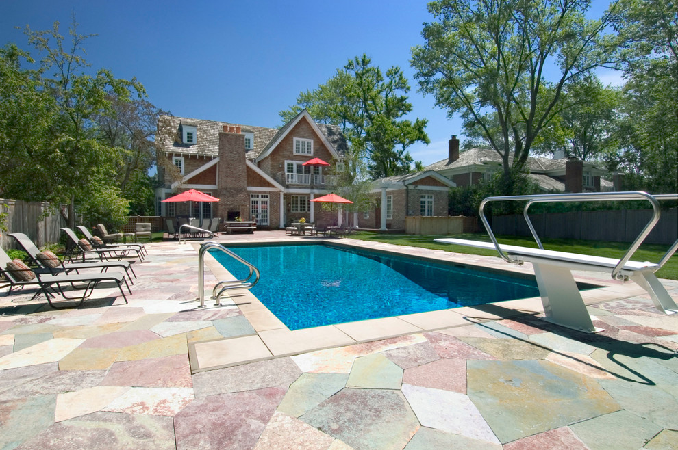 This is an example of a mid-sized traditional backyard rectangular lap pool in Chicago with natural stone pavers.
