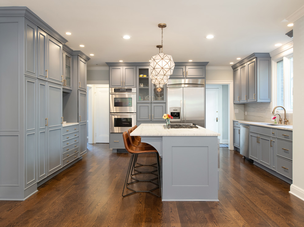Inspiration for a transitional u-shaped kitchen in Kansas City with an undermount sink, recessed-panel cabinets, grey cabinets, stainless steel appliances, dark hardwood floors, with island, brown floor and white benchtop.