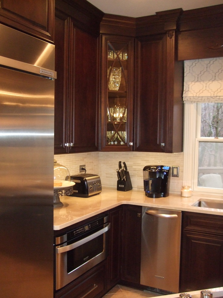 Example of a large transitional kitchen design with a single-bowl sink, raised-panel cabinets, dark wood cabinets, marble countertops, stainless steel appliances and an island