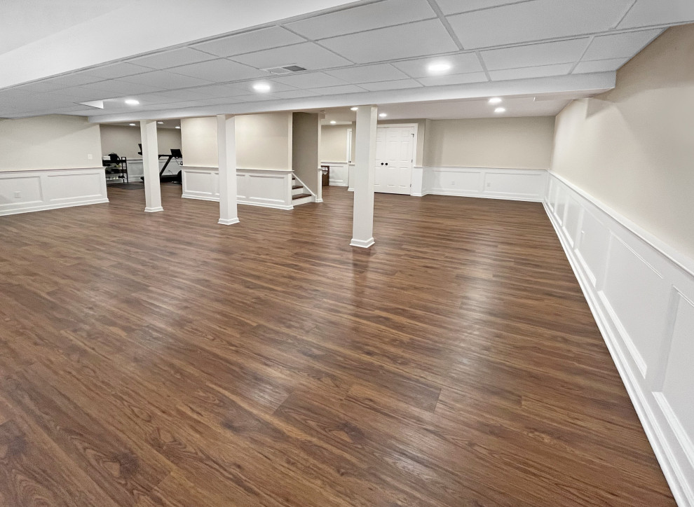 Photo of a large classic fully buried basement in Philadelphia with vinyl flooring, brown floors and wainscoting.