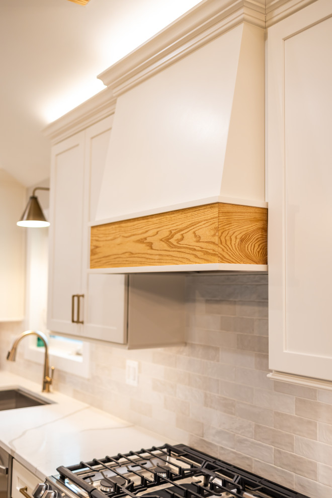 Large transitional l-shaped light wood floor, brown floor and exposed beam eat-in kitchen photo in DC Metro with an undermount sink, shaker cabinets, quartz countertops, white backsplash, porcelain backsplash, stainless steel appliances, an island and white countertops