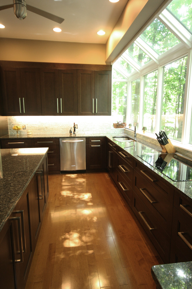 Example of a mid-sized transitional u-shaped light wood floor and beige floor enclosed kitchen design in Ottawa with a double-bowl sink, recessed-panel cabinets, dark wood cabinets, granite countertops, metallic backsplash, glass tile backsplash, stainless steel appliances, an island and brown countertops