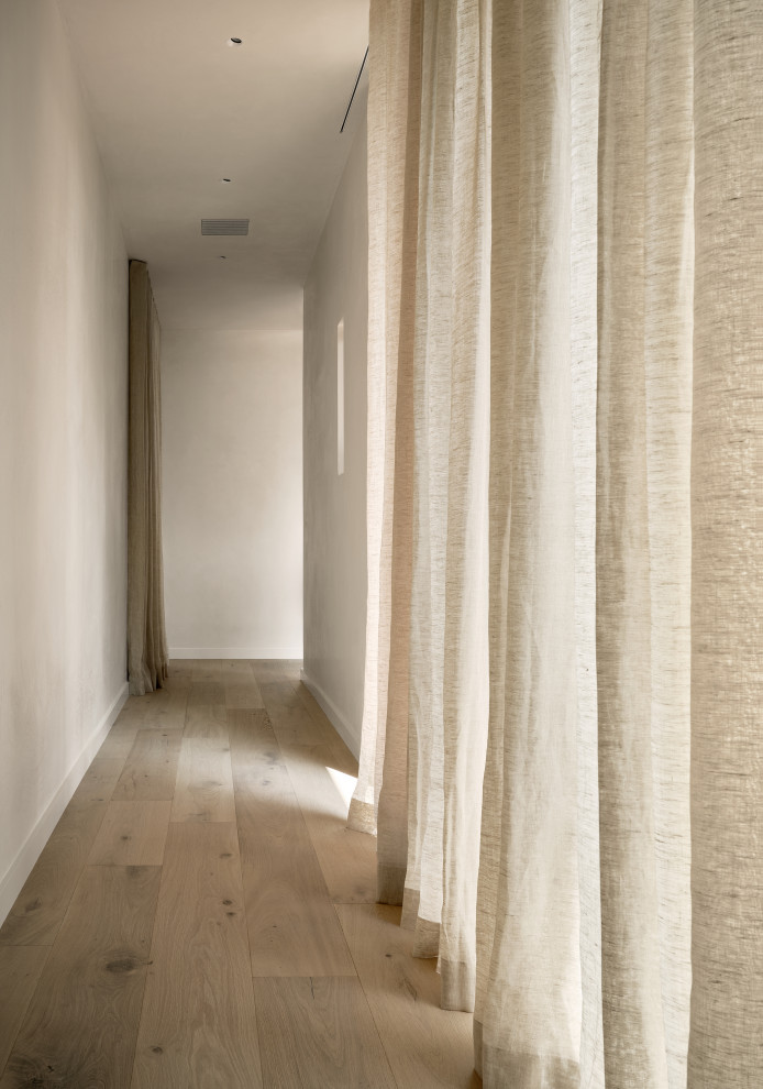 Imagen de recibidores y pasillos modernos pequeños con paredes blancas, suelo de madera clara y suelo beige