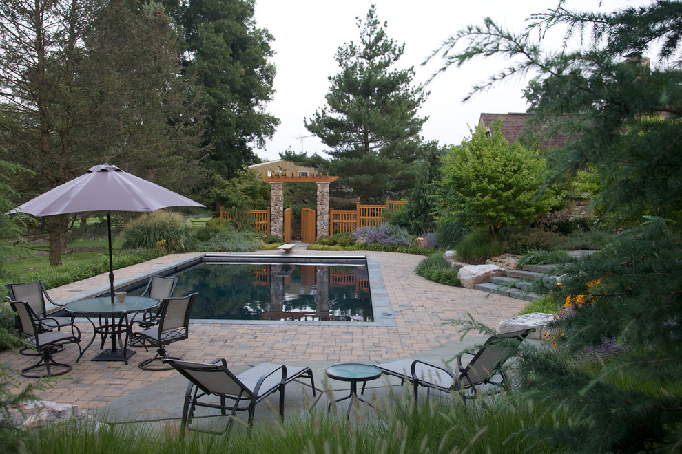 Design ideas for a large country backyard rectangular natural pool in DC Metro with brick pavers.