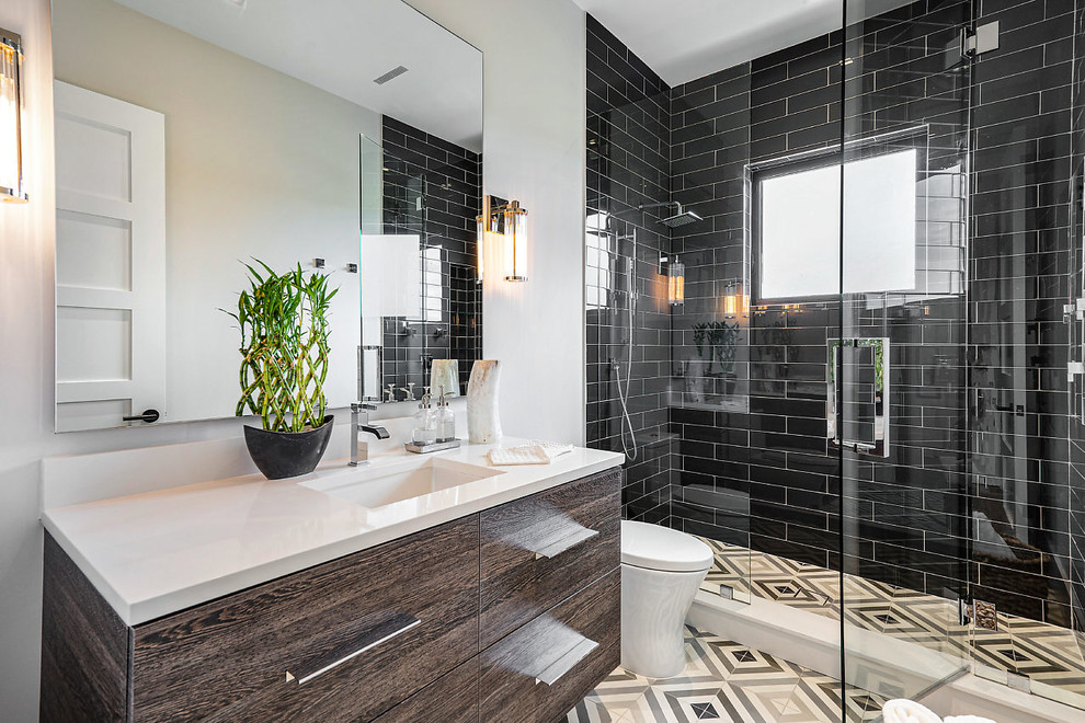 Photo of a beach style 3/4 bathroom in Other with flat-panel cabinets, brown cabinets, an alcove shower, black tile, subway tile, white walls, an undermount sink, multi-coloured floor, a hinged shower door and white benchtops.