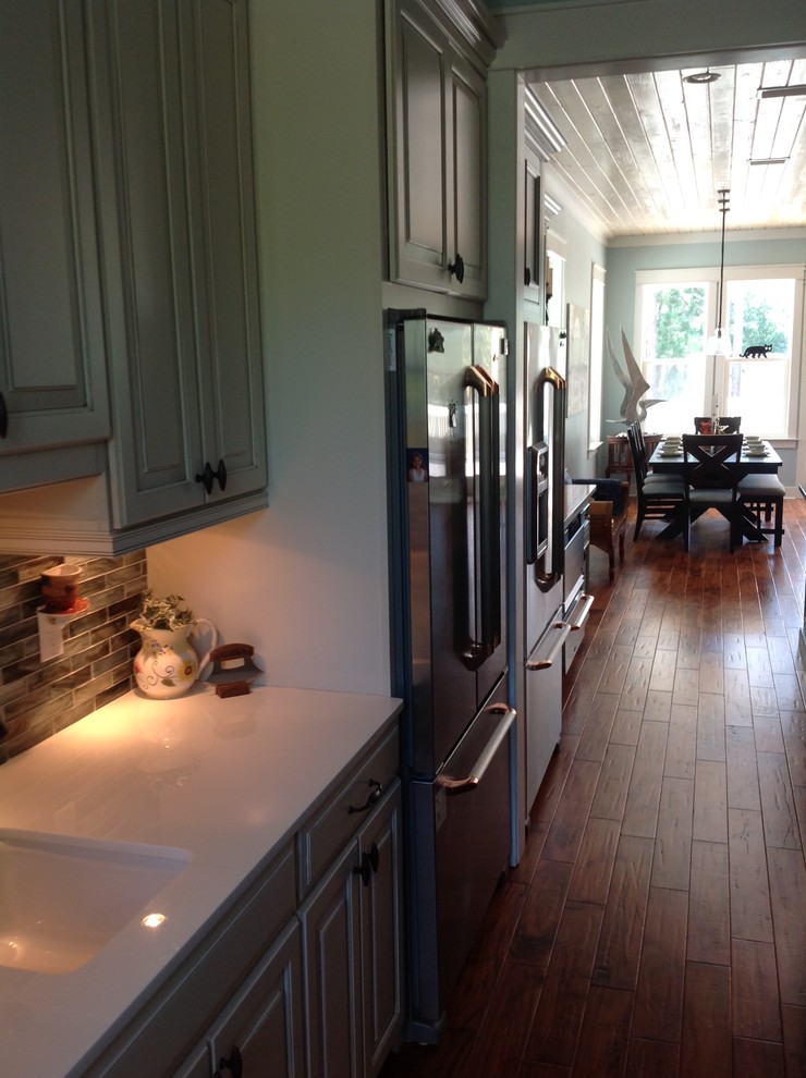 Example of a large transitional u-shaped porcelain tile eat-in kitchen design in Miami with an undermount sink, flat-panel cabinets, green cabinets, quartz countertops, multicolored backsplash, mosaic tile backsplash, stainless steel appliances and an island