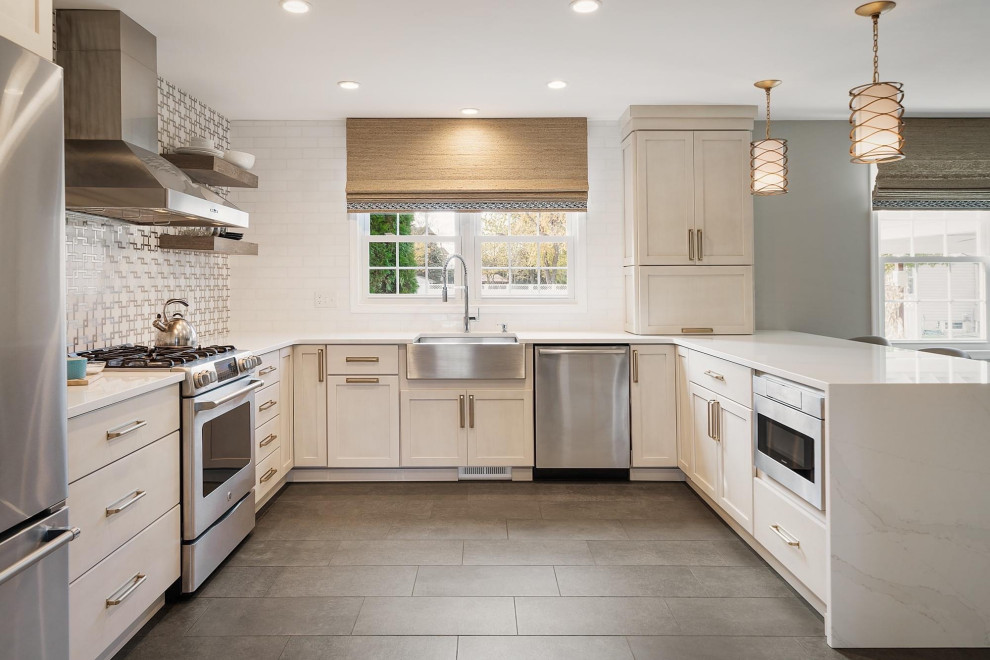 Inspiration for a transitional u-shaped gray floor kitchen remodel in Philadelphia with a farmhouse sink, shaker cabinets, white cabinets, gray backsplash, stainless steel appliances, a peninsula and white countertops