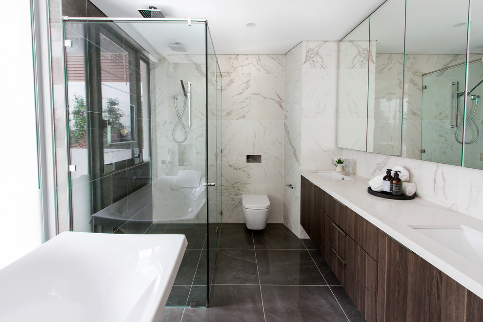 Inspiration for a large contemporary master bathroom in Sydney with flat-panel cabinets, white cabinets, a freestanding tub, brown walls, ceramic floors, a drop-in sink, a double shower, a one-piece toilet, marble, marble benchtops, black floor and a hinged shower door.