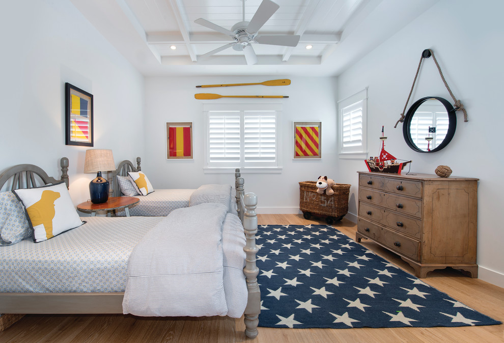 This is an example of a beach style kids' room for boys in Miami with light hardwood floors and white walls.