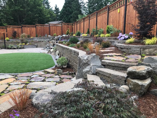 This is an example of a large transitional full sun backyard stone retaining wall landscape.
