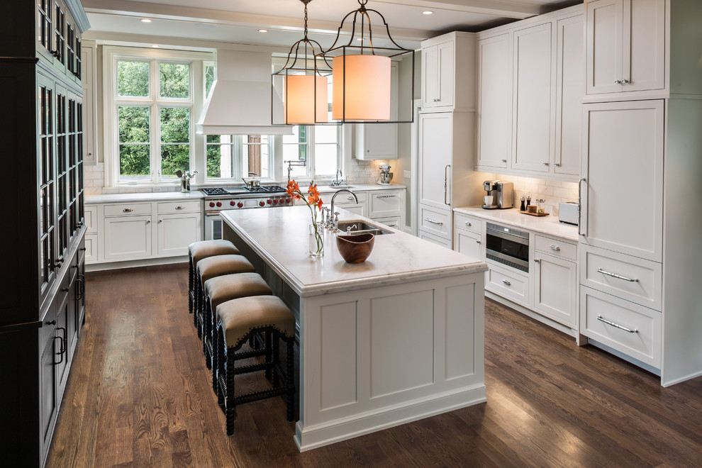 Design ideas for a large transitional u-shaped eat-in kitchen in Chicago with an undermount sink, recessed-panel cabinets, marble benchtops, white splashback, ceramic splashback, stainless steel appliances, dark hardwood floors, with island, brown floor and white cabinets.