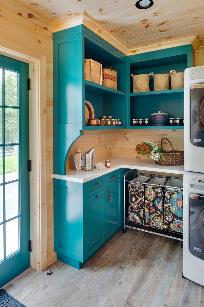 Inspiration for a mid-sized country l-shaped dedicated laundry room in Boston with ceramic floors, shaker cabinets, blue cabinets, a side-by-side washer and dryer, beige floor, white benchtop and wood walls.