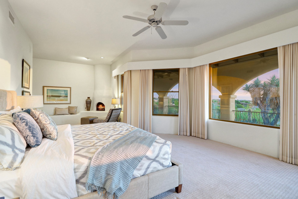 This is an example of a large master bedroom in Phoenix with white walls, carpet, a wood stove and grey floor.