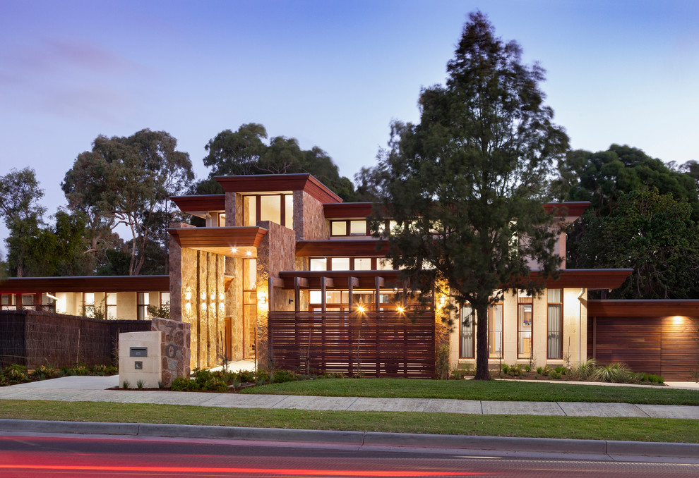 This is an example of a large contemporary two-storey multi-coloured house exterior in Melbourne with stone veneer, a flat roof and a metal roof.