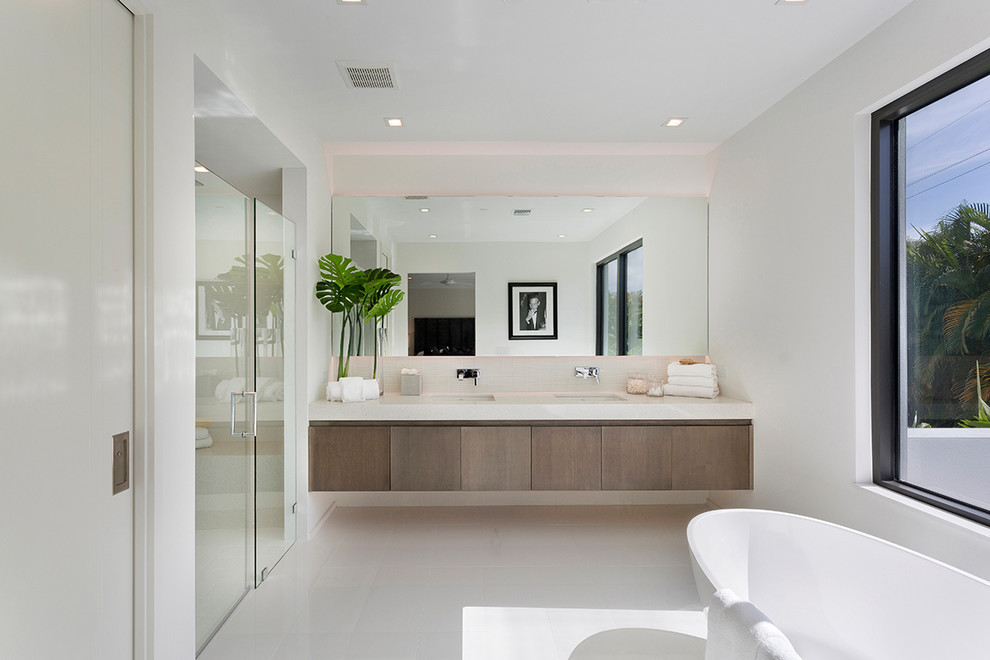 Inspiration for a mid-sized modern master bathroom in Other with flat-panel cabinets, dark wood cabinets, a freestanding tub, a curbless shower, a one-piece toilet, white tile, porcelain tile, white walls, porcelain floors, an undermount sink, engineered quartz benchtops, beige floor, a hinged shower door and white benchtops.