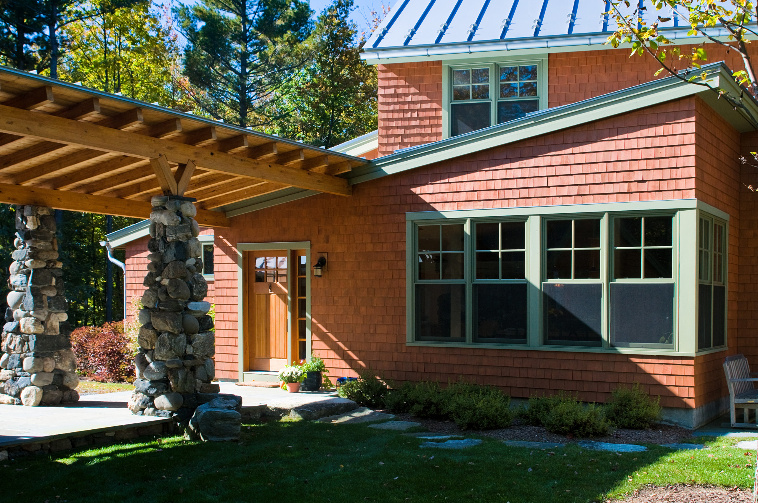 A laminated pine beam loggia connects the foyer to the garage/workshop, separating the parking area from the courtyard.
