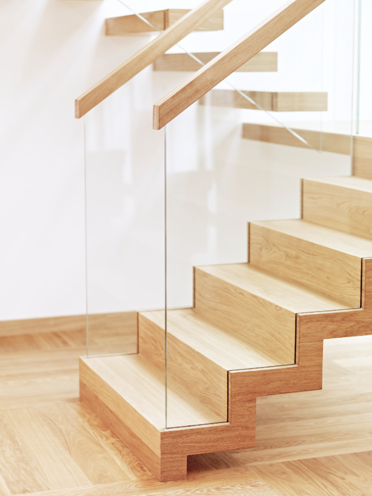 Ejemplo de escalera en U actual con escalones de madera, contrahuellas de madera y barandilla de vidrio
