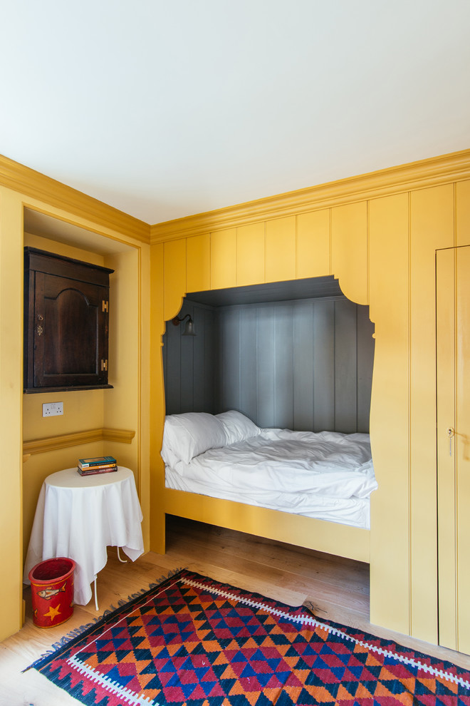 Mid-sized traditional guest bedroom in Edinburgh with yellow walls, medium hardwood floors and no fireplace.