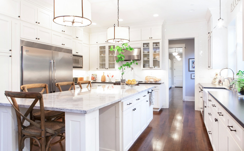 Example of a transitional u-shaped eat-in kitchen design in Portland with a farmhouse sink, shaker cabinets, white cabinets, quartzite countertops, white backsplash, subway tile backsplash and stainless steel appliances