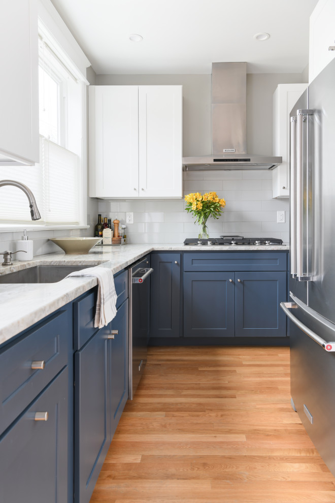 Kitchen - mid-sized transitional u-shaped light wood floor kitchen idea with an undermount sink, shaker cabinets, blue cabinets, solid surface countertops, white backsplash, porcelain backsplash, stainless steel appliances, no island and gray countertops