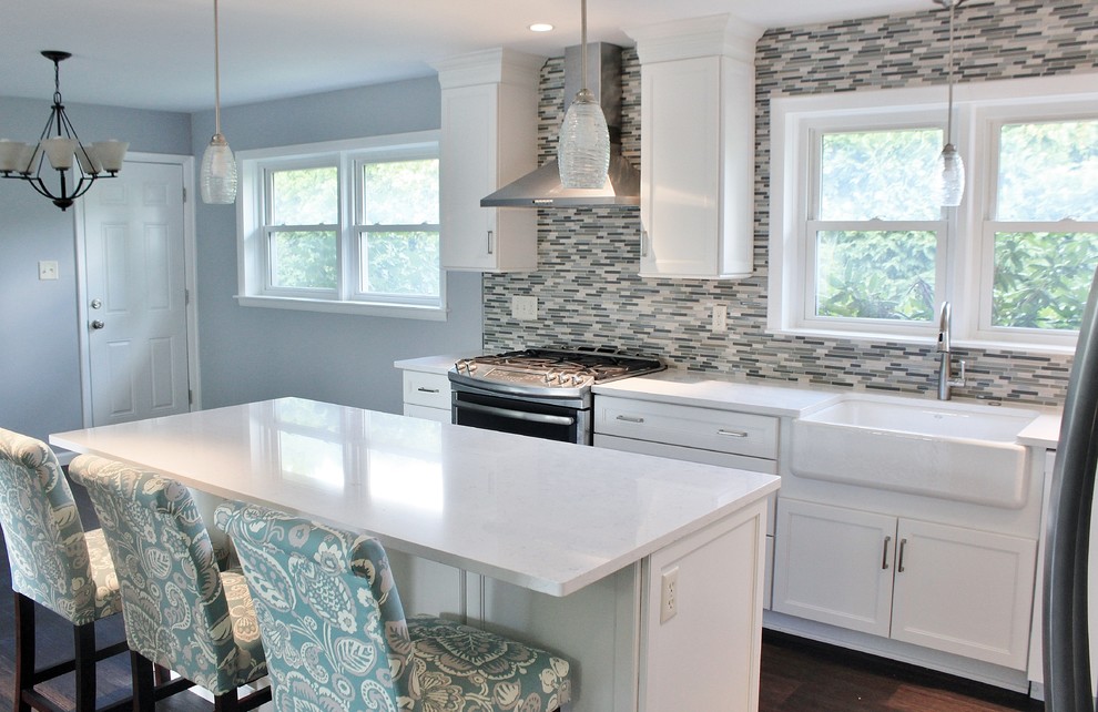 Photo of a mid-sized transitional l-shaped eat-in kitchen in Philadelphia with a farmhouse sink, shaker cabinets, white cabinets, quartz benchtops, blue splashback, mosaic tile splashback, stainless steel appliances, vinyl floors, with island and brown floor.