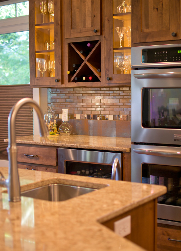 Large transitional l-shaped medium tone wood floor open concept kitchen photo with an undermount sink, flat-panel cabinets, medium tone wood cabinets, quartzite countertops, brown backsplash, ceramic backsplash, stainless steel appliances and an island